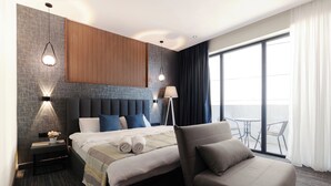 Una habitación de hotel moderna con una cama grande, un área de descanso y un balcón con vistas.