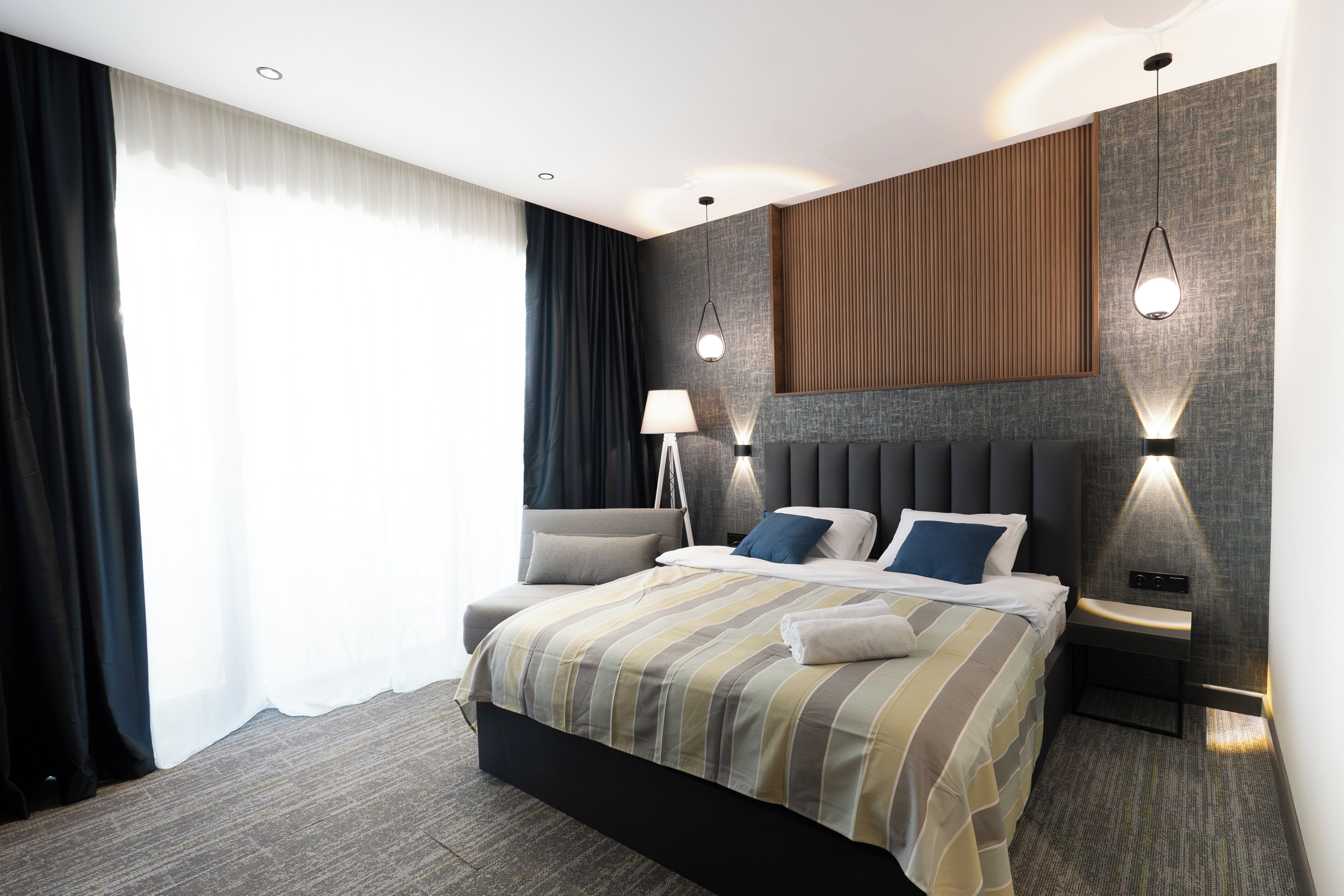 Et moderne hotelværelse med en stor seng, sengeborde med lamper og udsigt til det fri.