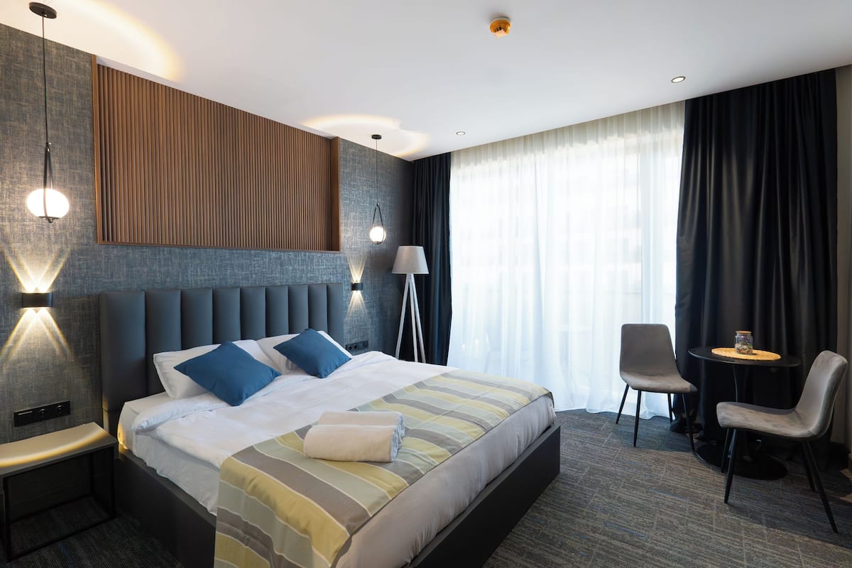 Une chambre d’hôtel moderne avec un grand lit, des lampes de chevet, un bureau et une chaise.