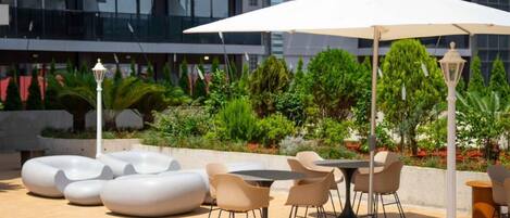 An outdoor patio with modern seating, a table, and a large umbrella.