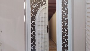 Una puerta blanca con diseños decorativos y un patrón de cuadrícula, que da a un pasillo.
