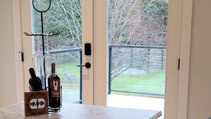 A modern kitchen with a marble countertop, black chairs, and a wine bottle. - Double D Ranch Guest House (Courtenay)