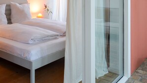 Een slaapkamer met een bed, nachtkastje, lamp en een raam met gordijnen.
