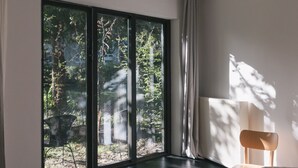 Een slaapkamer met een groot raam, een bed en een nachtkastje.