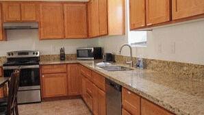 Una cocina con armarios de madera, encimeras de granito, electrodomésticos de acero inoxidable y suelo de baldosas.
