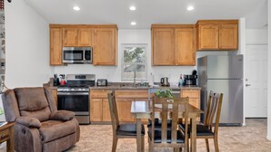 A modern kitchen with wooden cabinets, stainless steel appliances, and a dining area with a brown leather chair and wooden table. - Waterfront,  family resort, 2 separate units, Sauna, and Jacuzzi/ sleeps 8 (Kernville)