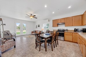 A spacious kitchen with wooden cabinets, a dining area with a table and chairs, and a ceiling fan.