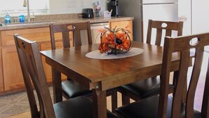 Un comedor con mesa y sillas de madera, una cocina con armarios de madera y un refrigerador.