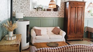 A cozy room with a white sofa, a wooden cabinet, a checkered tablecloth-covered table, and a hanging light fixture. - Group gîte with single rooms, no dormitories, in the heart of nature. (Le Chambon-sur-Lignon)