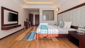 A modern hotel bedroom with a large bed, a TV mounted on the wall, a bedside table, and a patterned headboard. - Hotel Samaya (Leh)