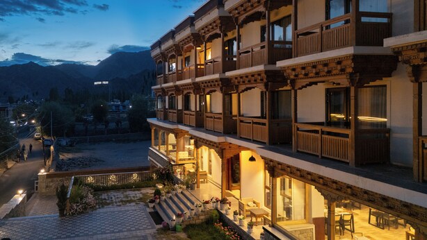 A multi-story building with traditional architecture, featuring balconies and a courtyard with potted plants. - Hotel Samaya (Leh)