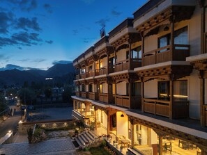 Un edificio de varios pisos con arquitectura tradicional, con balcones y un patio con plantas en macetas.
