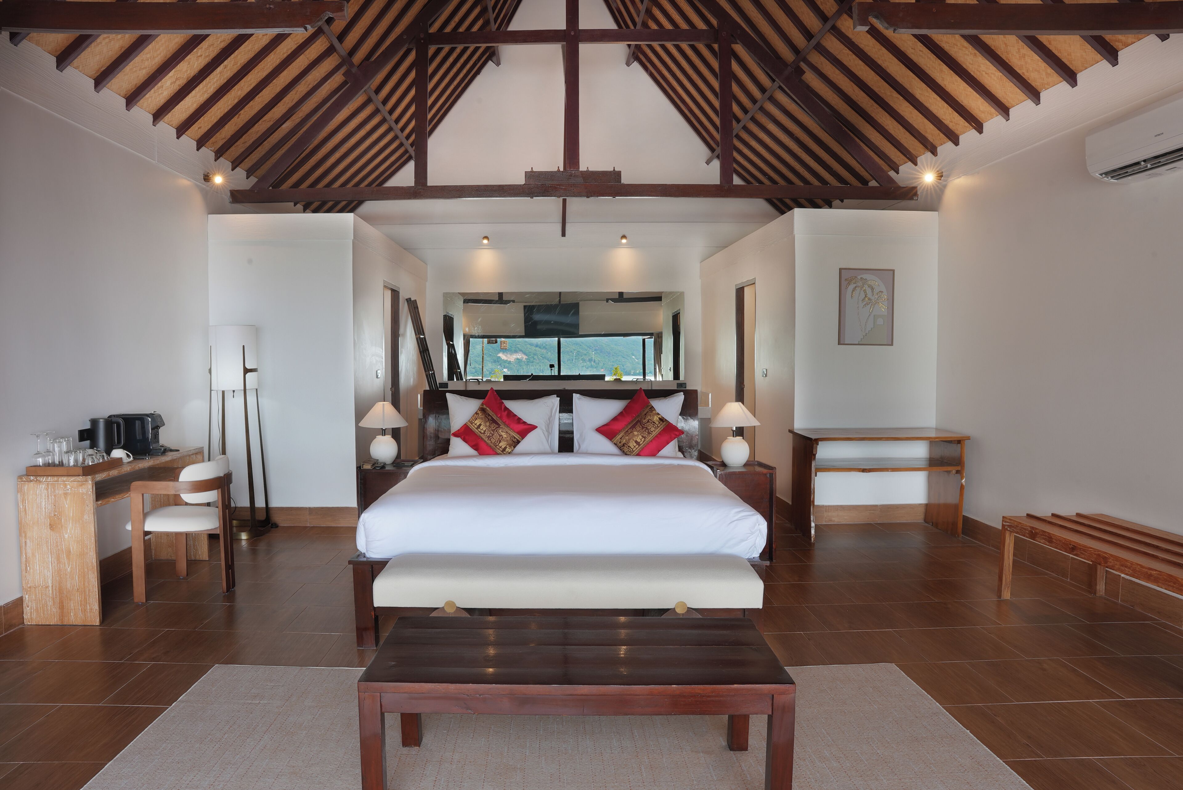 A spacious bedroom with a large bed, wooden furniture, and a view of the outdoors.