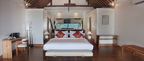 A spacious bedroom with a large bed, wooden furniture, and a view of the outdoors.