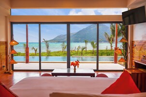 Habitación de hotel con una ventana grande que ofrece vistas a una piscina y montañas.