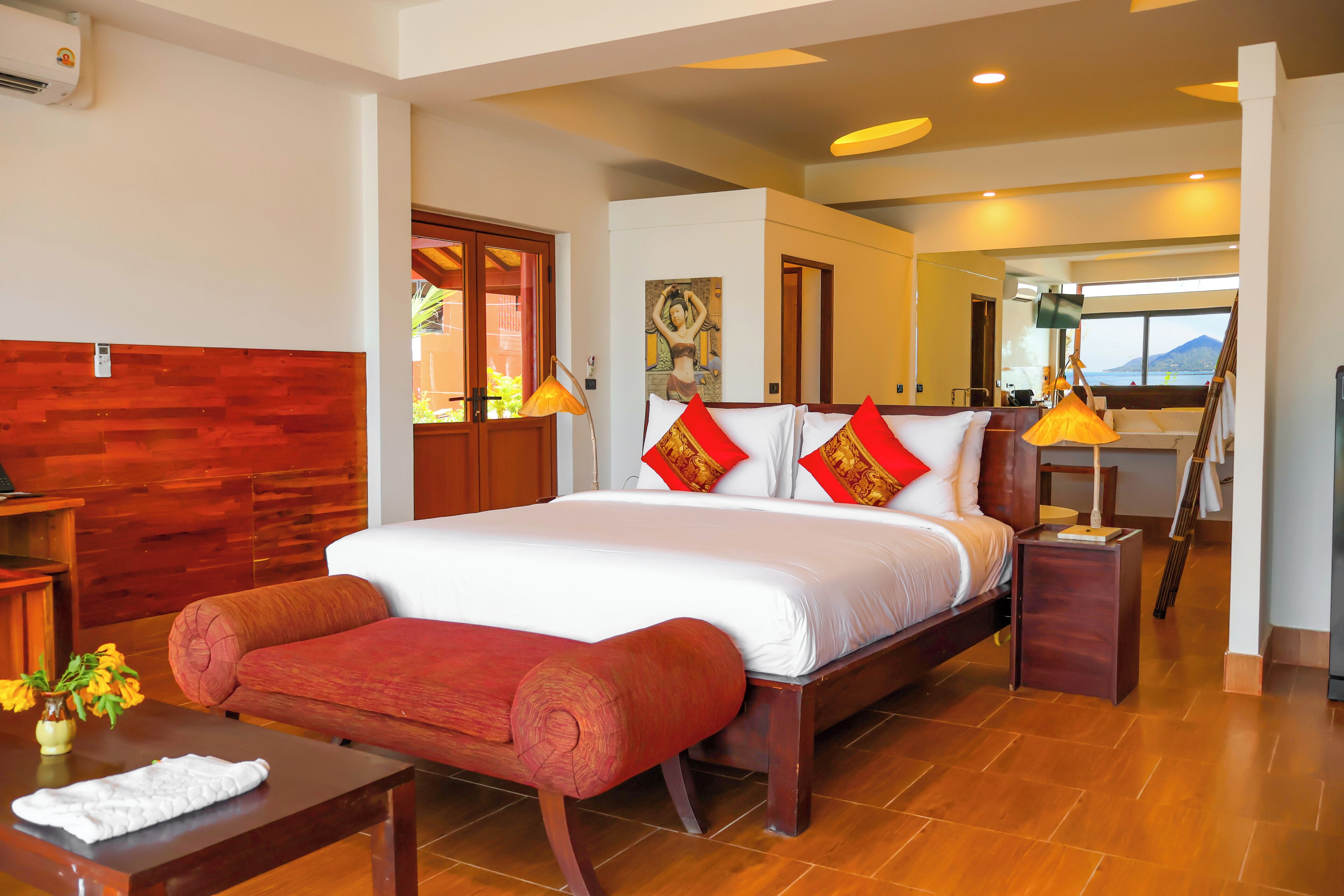 Un dormitorio amplio con una cama grande, cabecera de madera y un banco rojo.