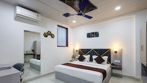 A modern bedroom with a bed, bedside tables, a desk, and an air conditioning unit. - Hotel Warm Welcome Inn Noida Sector 26 (Noida)