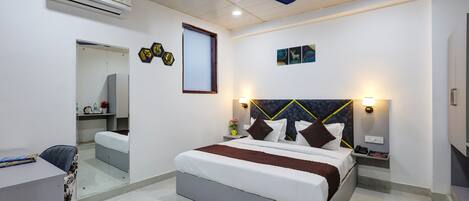 A modern bedroom with a bed, bedside tables, a desk, and an air conditioning unit.