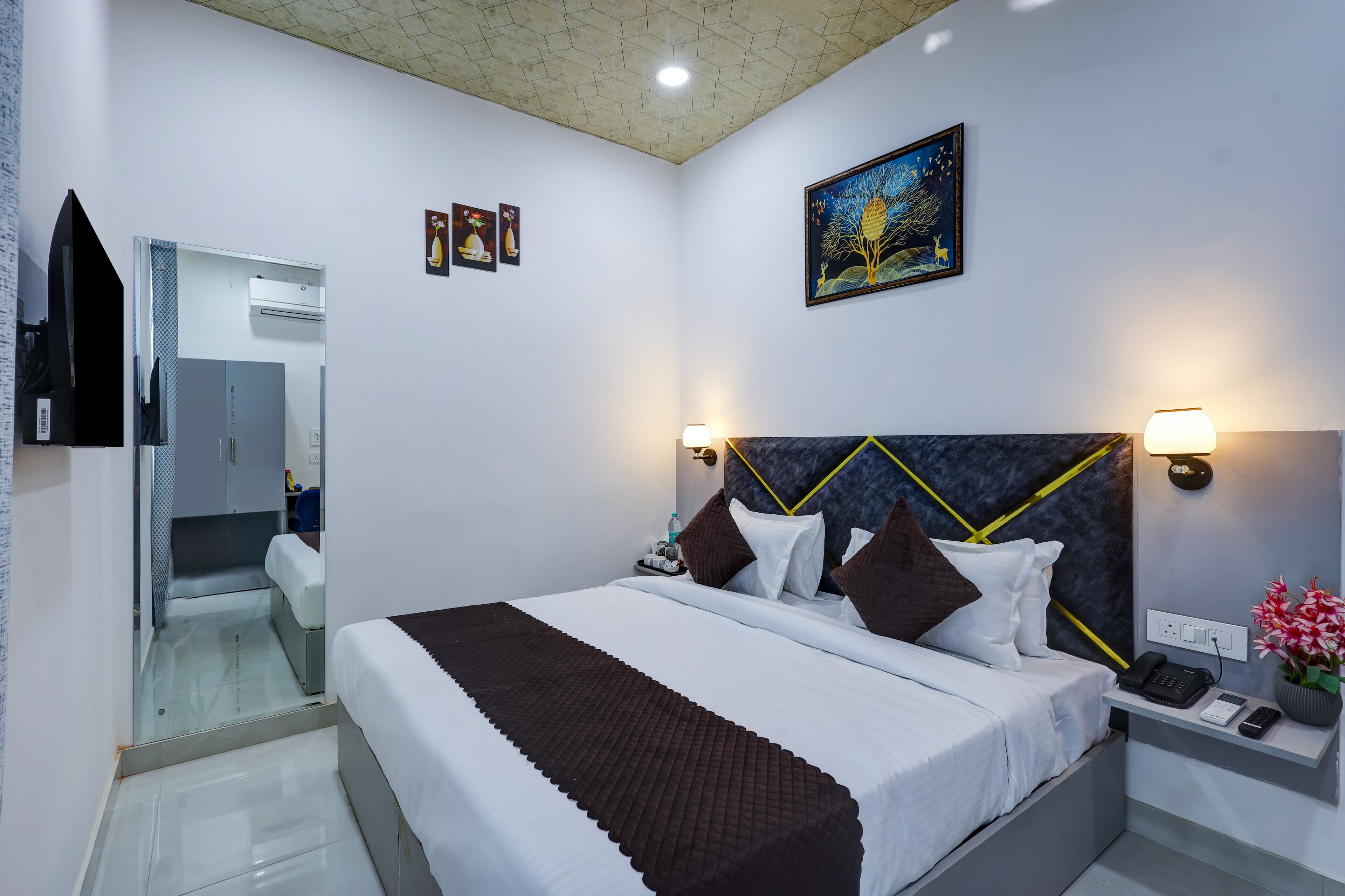 A modern hotel room with a bed, bedside table, and a mirror.