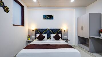 Una habitación de hotel moderna con una cama grande, mesitas de noche, un armario y obras de arte colgadas en la pared.