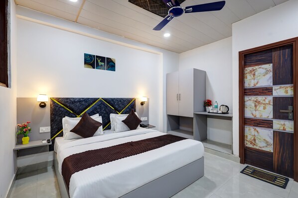 Une chambre à coucher moderne, équipée d’un lit, de tables de chevet, d’un ventilateur de plafond et d’une armoire.