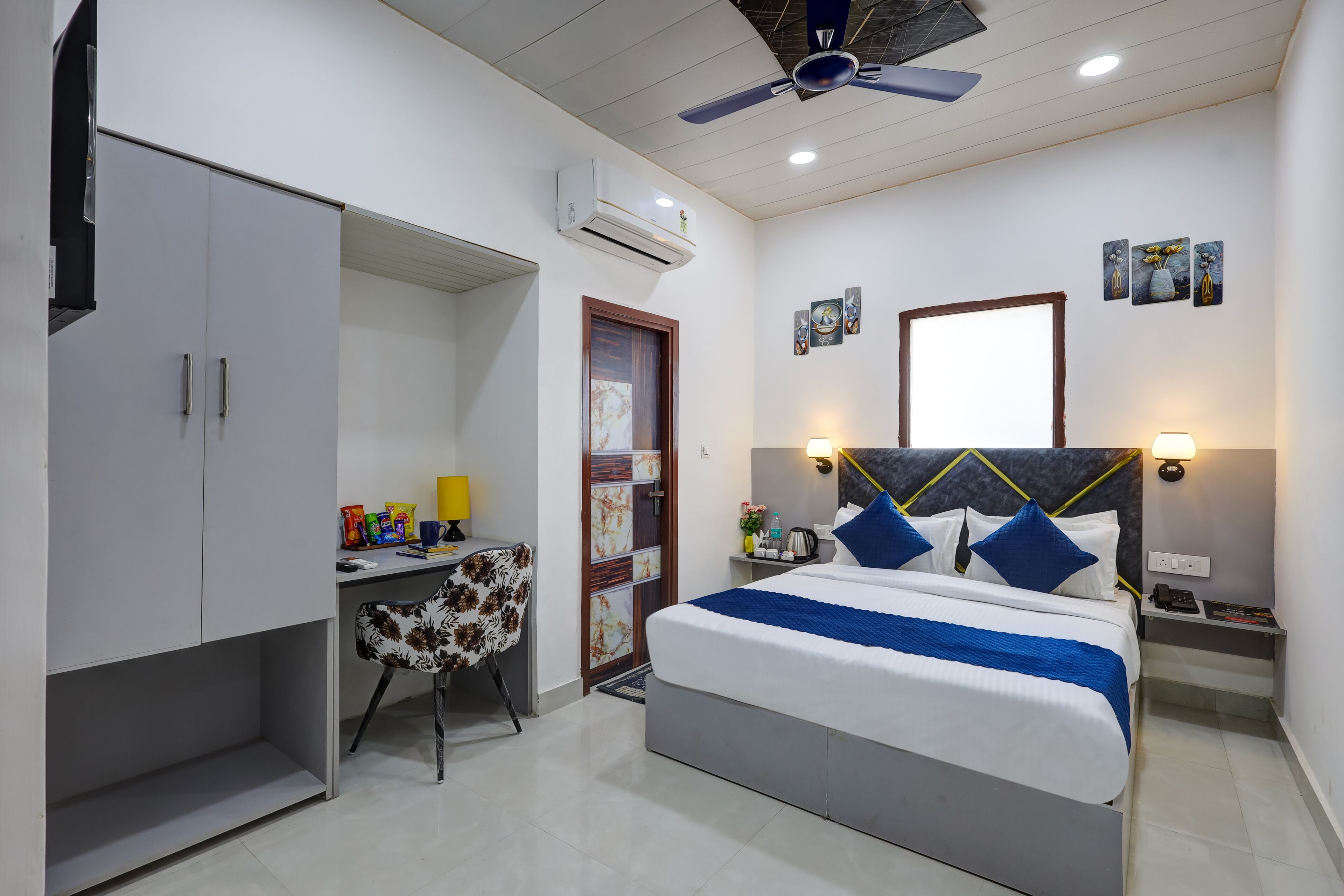 A bedroom with a bed, desk, chair, and a wardrobe.