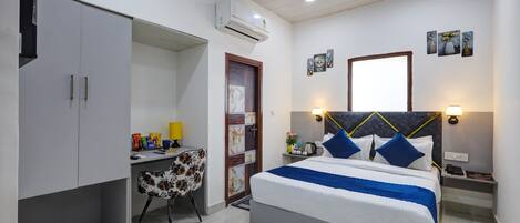 A bedroom with a bed, desk, chair, and a wardrobe.