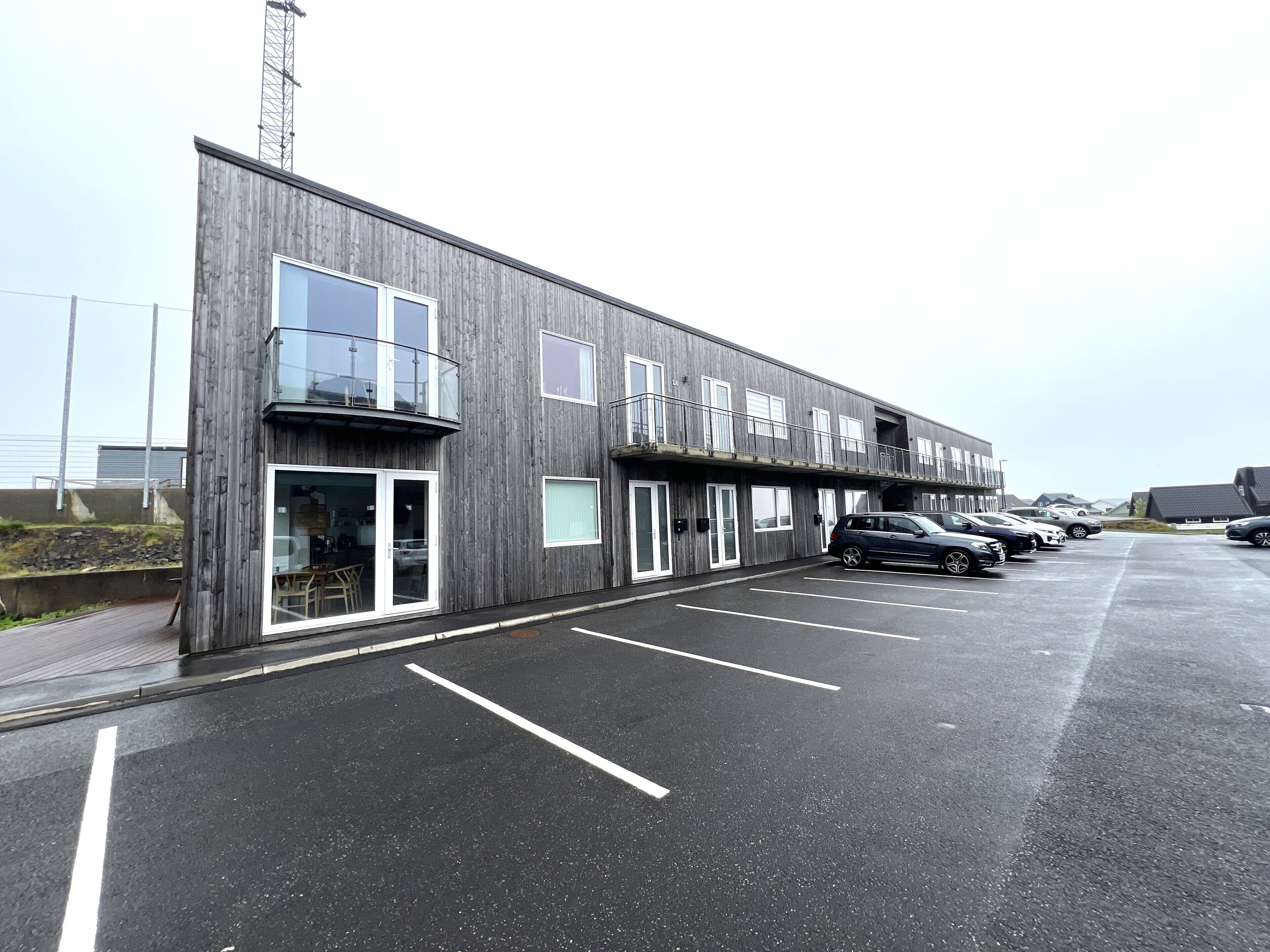 A modern building with a parking lot and several cars.