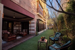 A courtyard with outdoor seating, a small table with fruit, and a view of a building with a balcony.