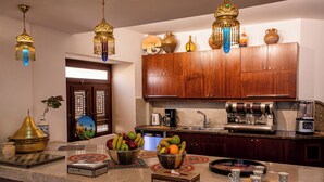 A kitchen with wooden cabinets, a coffee maker, and a fruit bowl on the counter.