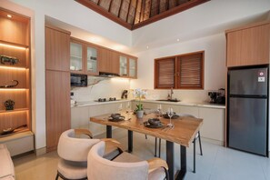 A modern kitchen with wooden cabinets, a dining table with chairs, and a built-in oven.