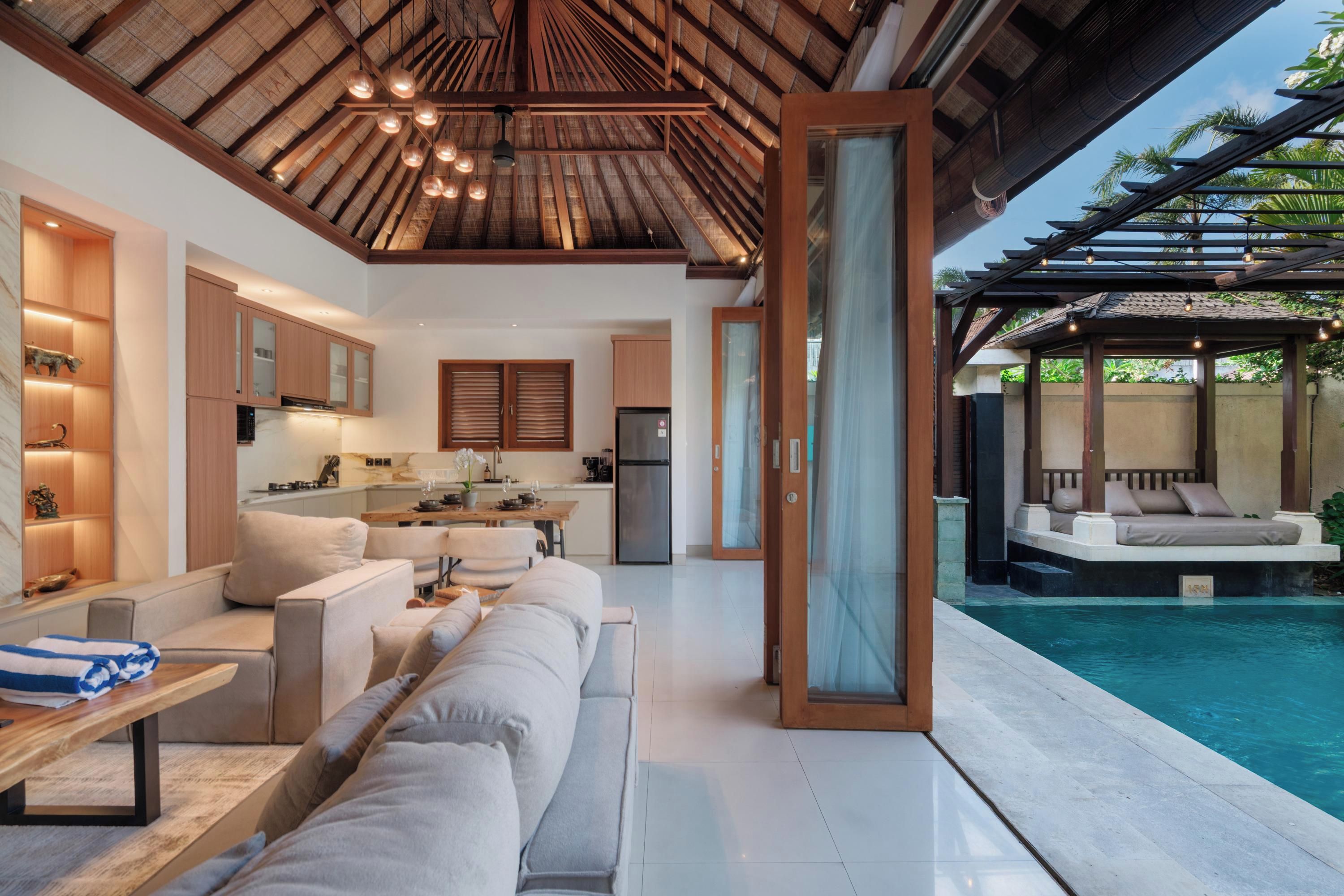 A modern interior with a dining area, kitchen, and a poolside seating area.
