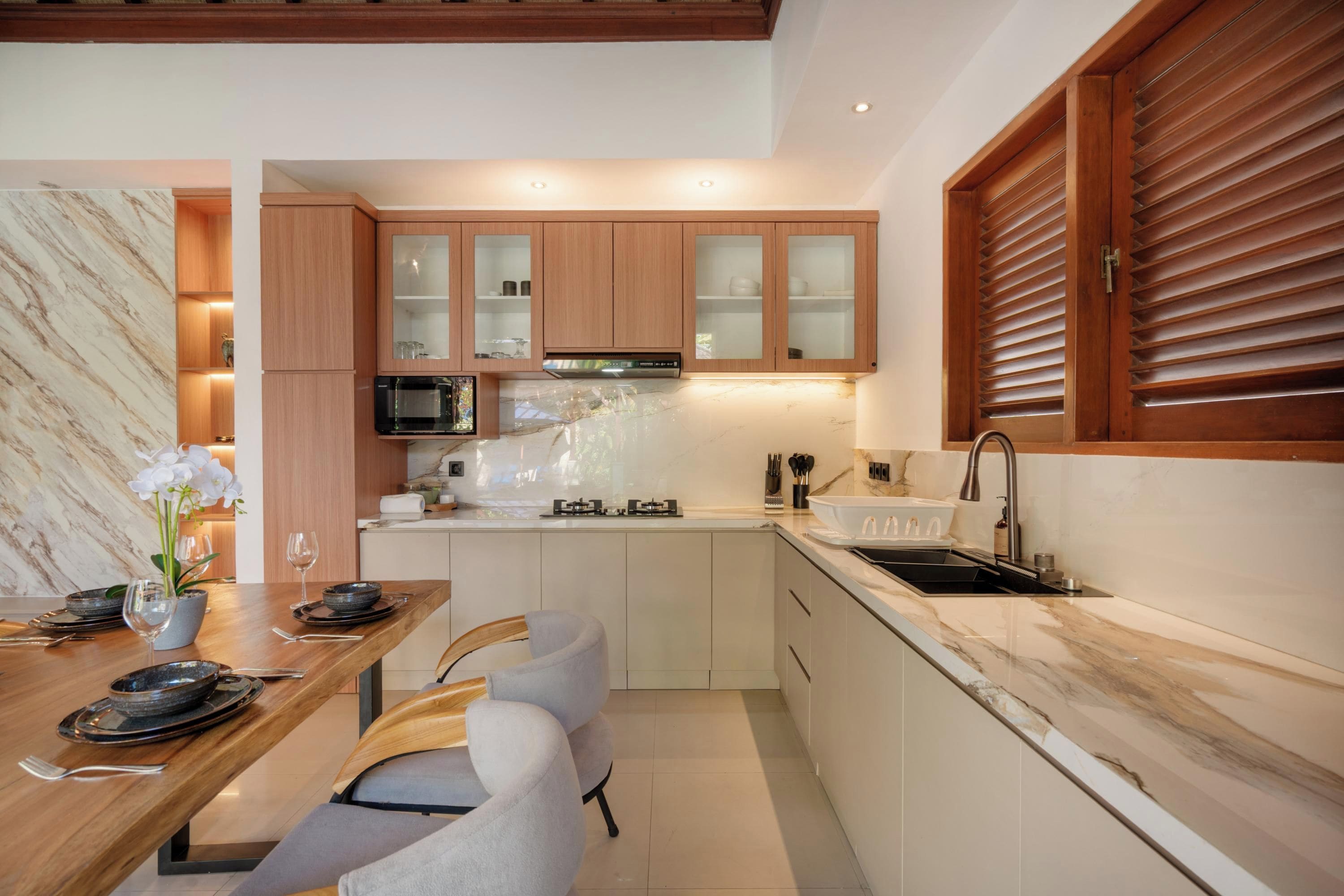 Una cocina moderna con armarios de madera, un microondas integrado y un lavamanos de acero inoxidable.