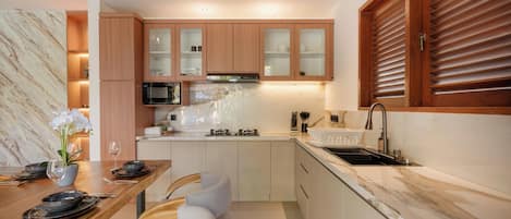A modern kitchen with wooden cabinets, a built-in microwave, and a stainless steel sink.