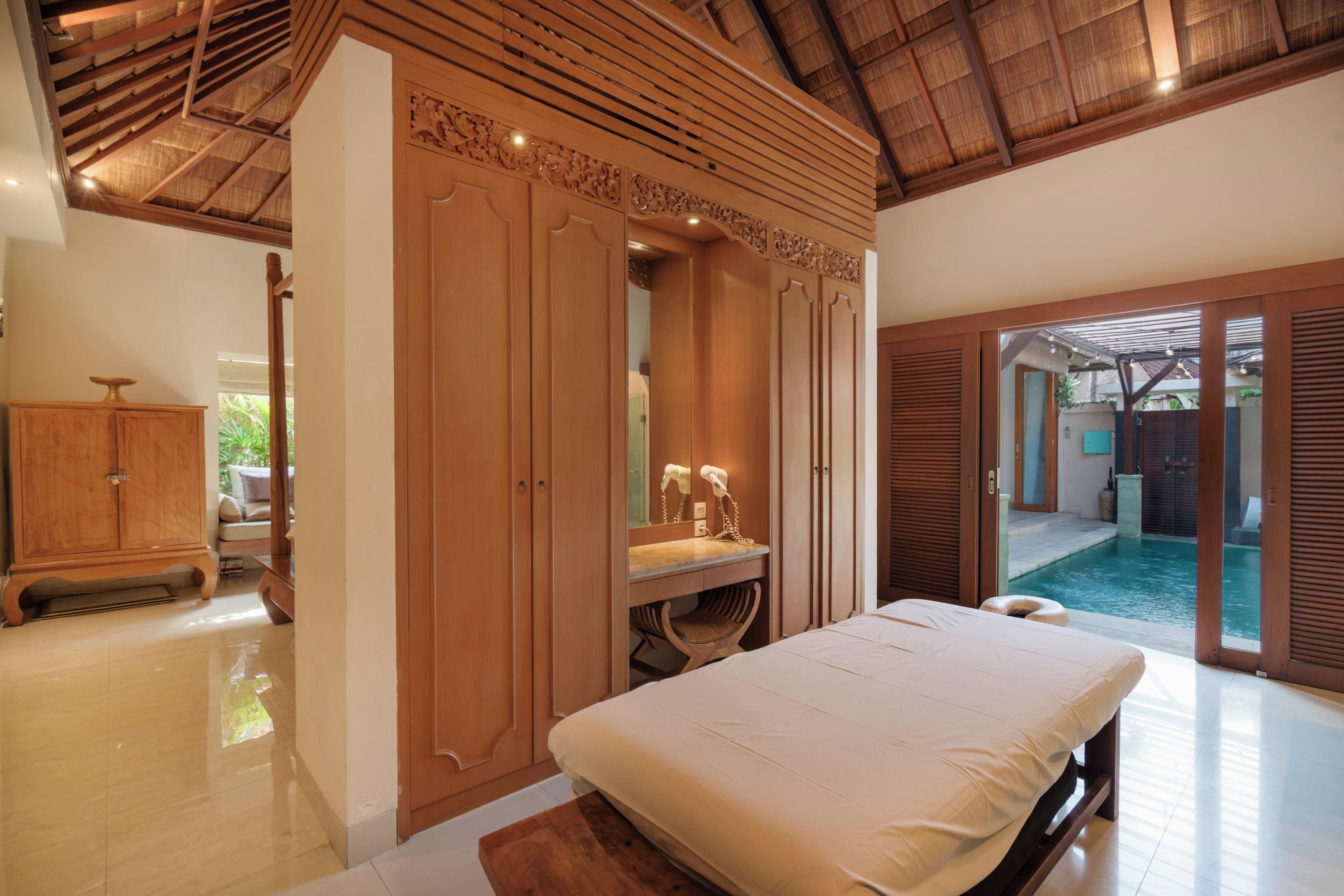 Une chambre avec un lit, une coiffeuse avec un miroir et une vue sur une piscine extérieure.
