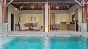 Un espace aménagé au bord de la piscine, comprenant un coin salon, une cuisine et un coin repas.