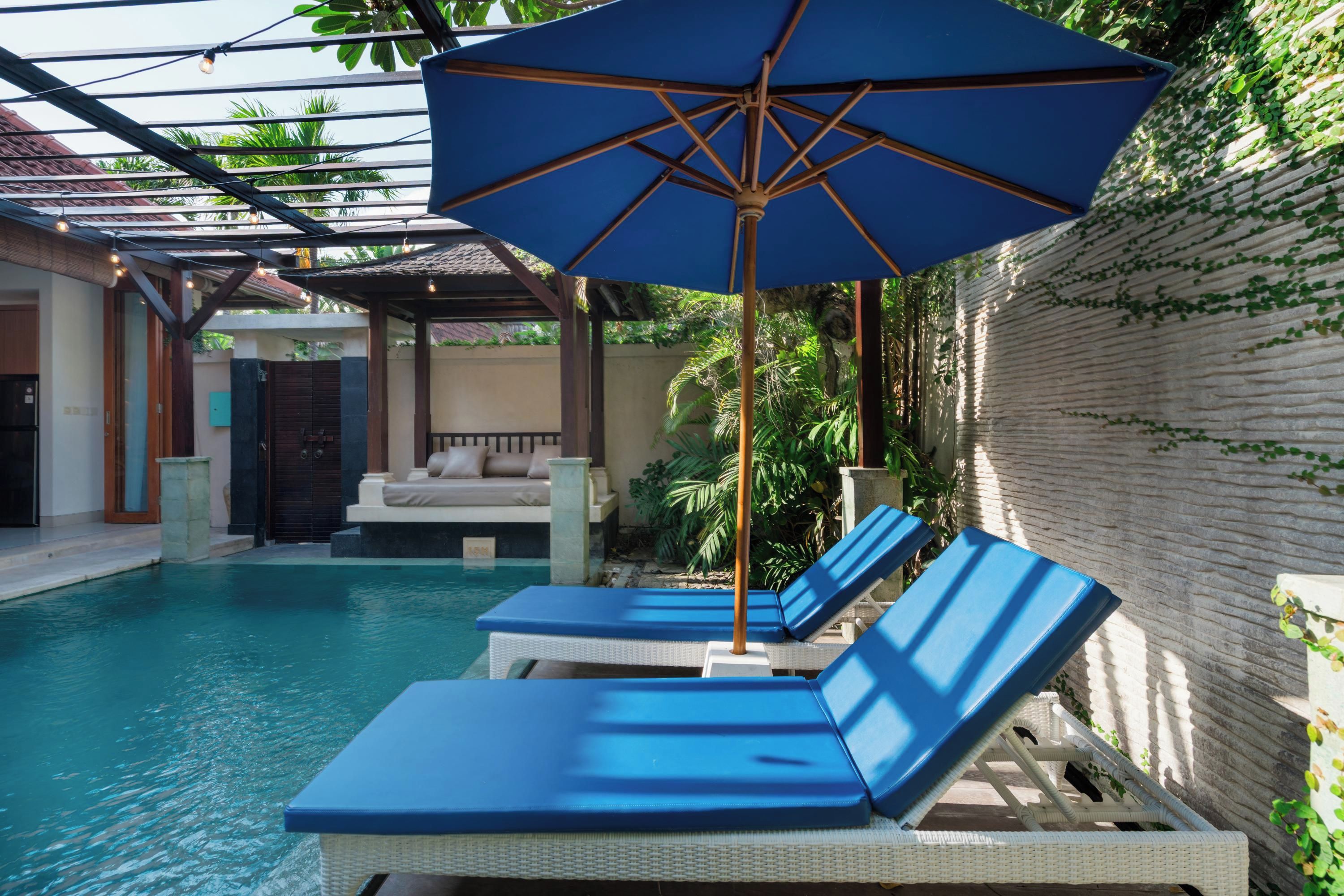 Zona de piscina con sillones de descanso y una sombrilla grande.
