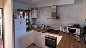 A kitchen with white cabinets, a dishwasher, an oven, a microwave, and a sink.
