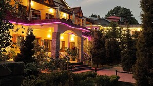 A large building with a balcony, a staircase, and a well-lit entrance. - Shri Shail Inn (Dhari)