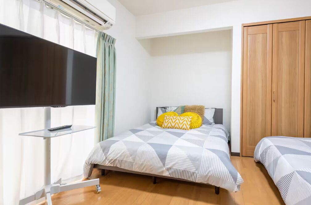 Une chambre d’hôtel avec un lit, une télévision, une armoire et une fenêtre avec des rideaux.