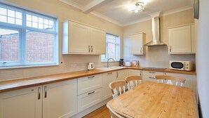 Una cocina moderna con armarios blancos, encimera de madera y una mesa de comedor con sillas.