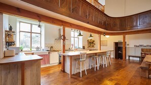 Cocina amplia con pisos de madera, una isla central con taburetes y vistas al exterior a través de grandes ventanales.