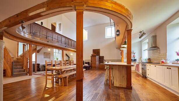 Una cocina amplia con pisos de madera, un comedor y una entreplanta con escalera.