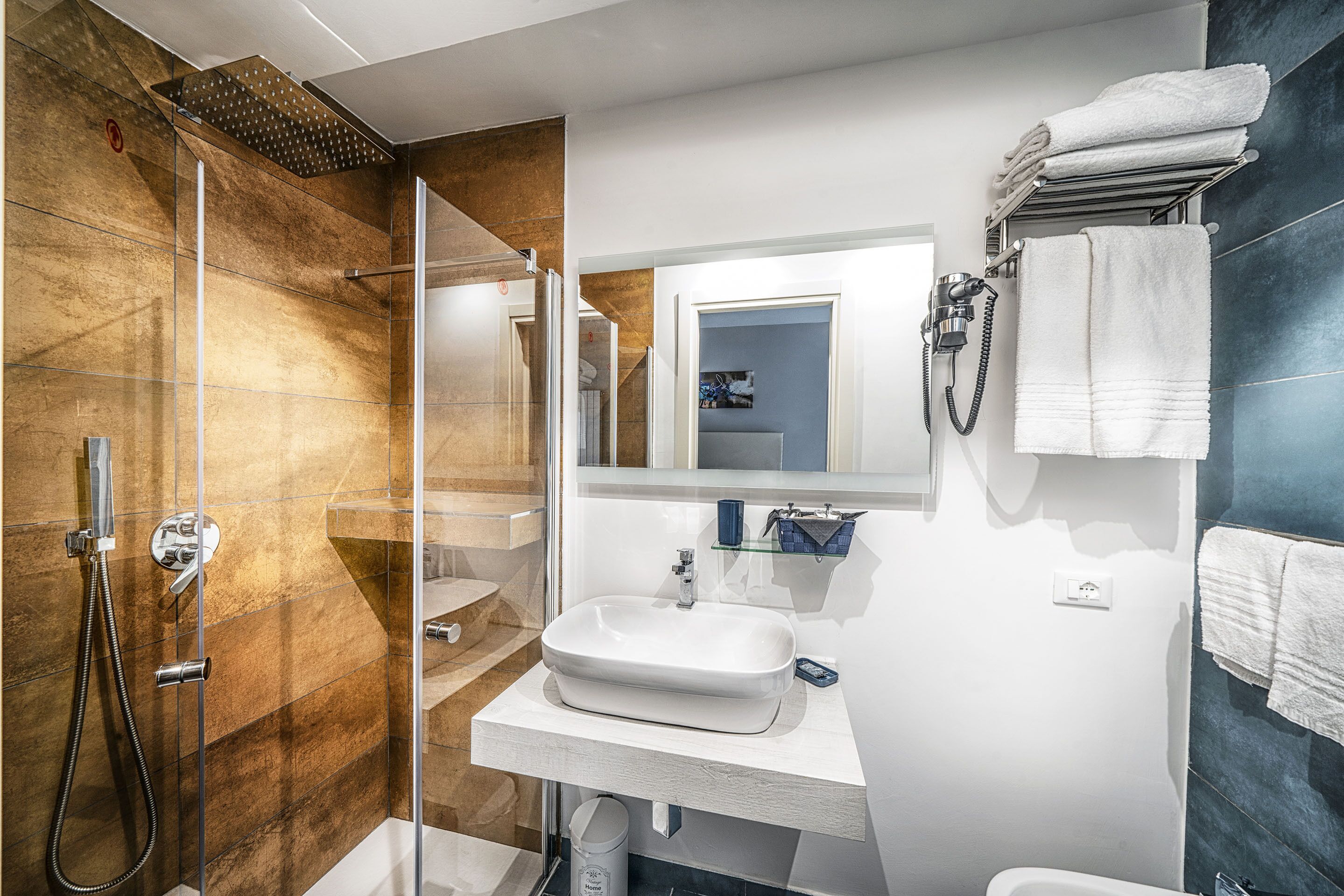 A modern bathroom with a glass-enclosed shower, a white sink, and a towel rack.
