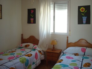 Two single beds with leaf-patterned duvets, wooden headboards, and lamps.