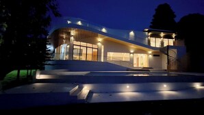 A modern house with a curved facade, large windows, and a staircase leading to a covered entrance. - Celine House by Craft Village (Koh Samui)