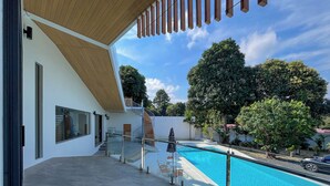 A modern building with a pool, outdoor seating, and a staircase leading to a balcony. - Celine House by Craft Village (Koh Samui)