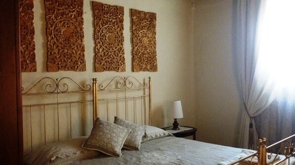 A bed with a metal headboard, two pillows, and a bedside table with a lamp.