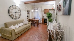 A living room with a sofa, a dining table, and chairs. There is a large wall clock and a chandelier. - FLORENCE TOWER APARTMENT (Firenze)