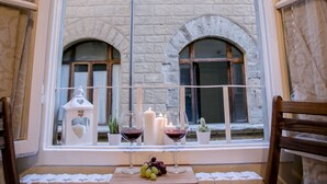 A room with a large window overlooking a stone building, a table with candles, wine glasses, and a fruit basket. - FLORENCE TOWER APARTMENT (Firenze)